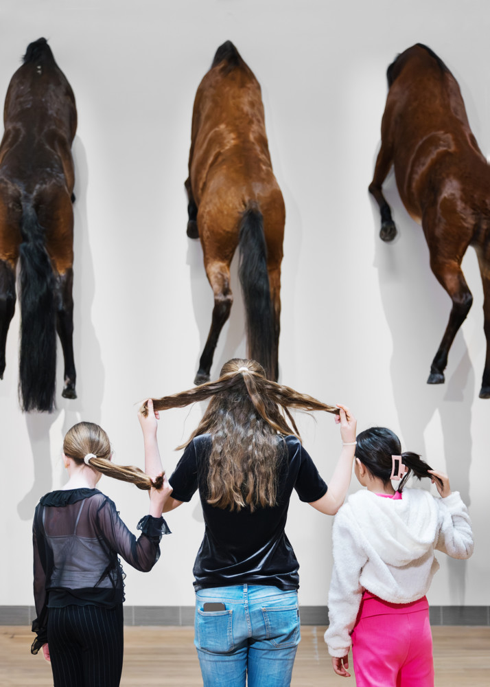 three children looking att horses on wall