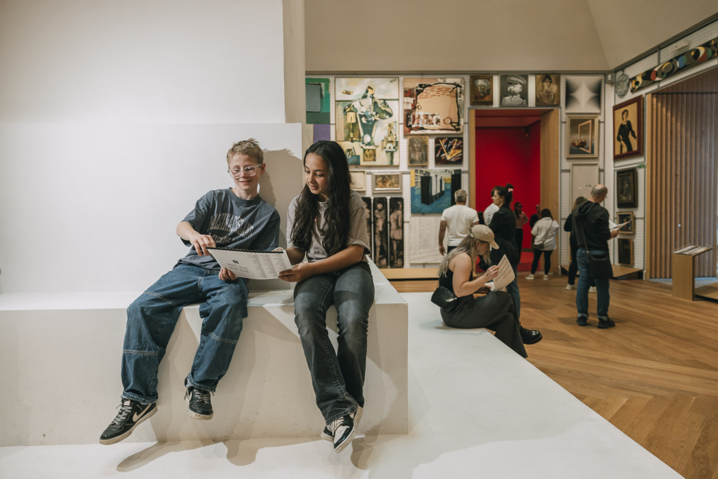 Two persons sitting on the sculpture "Untitled" in the exhibition Te third hand