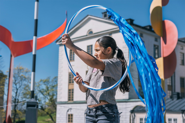 A child holds a hula-hoop with plastic fringes on it