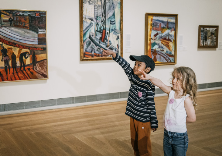 Two children pointing towards an artwork