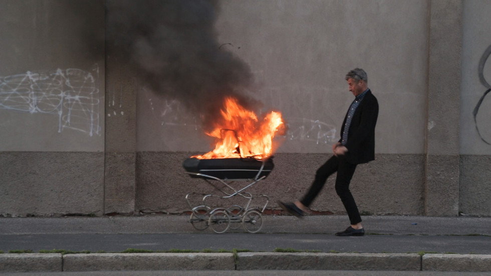 Person kicking a burning stroller on a sidewalk